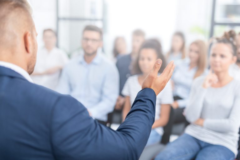 Man speaking to a group of seated individuals.