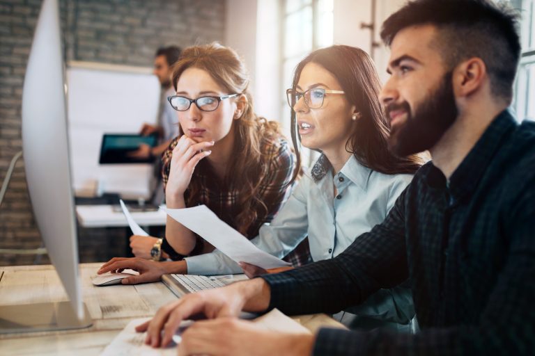 Three employees looking at a computer together.