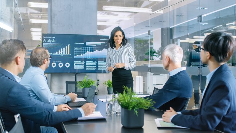 Businesswoman Giving a presentation to colleagues in conference room setting.